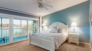 Una camera da letto con un letto grande, due comodini, una ventola a soffitto e un balcone con vista.