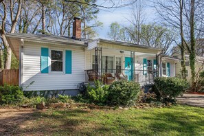 Une maison à deux étages avec un porche, une cheminée et un petit jardin.