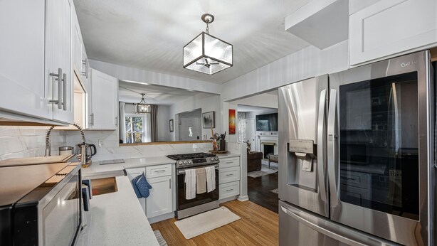 A modern kitchen with stainless steel appliances, white cabinetry, and a wooden floor. - Charming 3-bedroom house in cool Hapeville neighborhood (Hapeville)