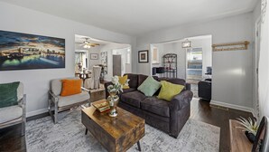 A living room with a dark brown sofa, a wooden coffee table, and a painting of a cityscape. - Charming 3-bedroom house in cool Hapeville neighborhood (Hapeville)