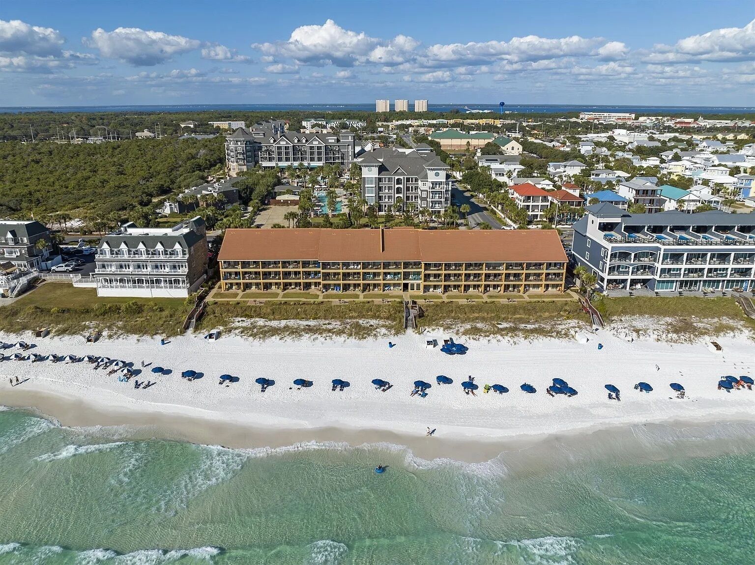 A beachfront hotel with multiple stories, a sandy beach, and ocean views.