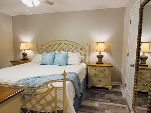 A neatly arranged bedroom with a bed, two bedside tables with lamps, a wooden chair, and a door with a mirror.