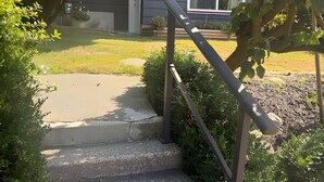 Una escalera conduce a una casa con un jardín cuidado y vistas despejadas del entorno.