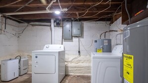 A laundry room with a washing machine, dryer, and utility room with electrical panels.