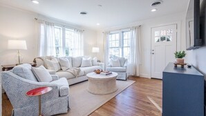 A modern living room with a sectional sofa, a round coffee table, and a flat-screen TV mounted on the wall.
