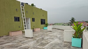 A rooftop terrace with a green wall, a white ladder, and potted plants. - Cozy 1-bedroom apartment in amazing Accra (Accra)
