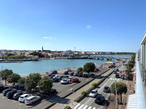 Ein Parkplatz neben einem Hafen mit Booten, einer Brücke und Gebäuden im Hintergrund.