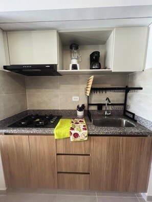 A compact kitchen with a gas stove, a built-in oven, a coffee maker, and a knife holder. - Modern and Quiet Apartment near the Beach (Santa Marta)
