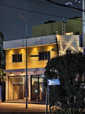 Un edificio moderno con fachada amarilla, amplios ventanales de vidrio y un letrero que indica un bar de bambú.
