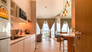Una cocina moderna con refrigerador, microondas y pileta. Hay un comedor con mesa y sillas, y vistas al exterior a través de amplios ventanales.