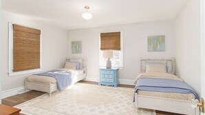 A bedroom with two beds, a nightstand, and a window with a view.
