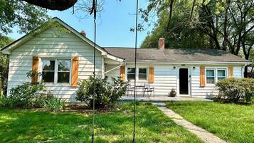 A single-story house with a front porch, a swing, and a pathway leading to the entrance.