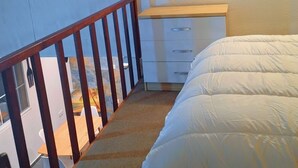 A bedroom with a wooden bed, a desk, and a chair. There is a staircase leading to another room. - Emma modern suite (2-minute walk from the beach). (Kourou)