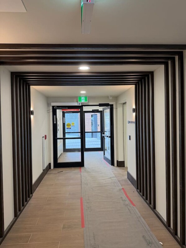 A hotel corridor with a double door entrance, a fire alarm, and a visible exit sign.