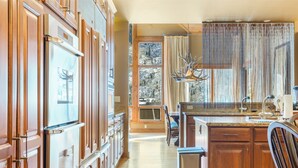 Un'ampia cucina con mobili in legno, una grande finestra con vista sugli alberi e un lampadario.