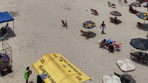 En strand med parasoller, stolar och en vattenyta.