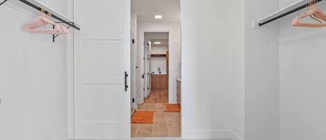 A hallway with a sliding door leading to a kitchen area.