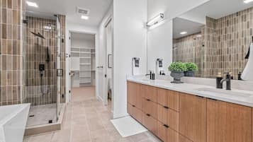 Ein modernes Badezimmer mit bodengleicher Dusche, einem großen Spiegel und einem Holzlagerfläschchen.
