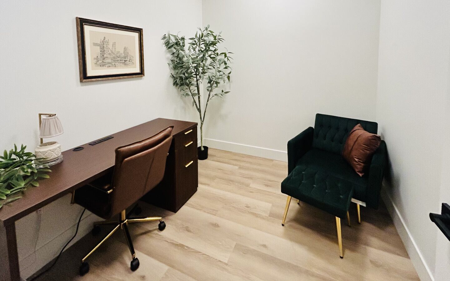 A room with a desk, chair, and a green sofa.