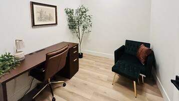 A room with a desk, chair, and a green sofa.