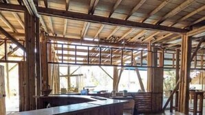 Un intérieur rustique en bois, avec un bar, des tabourets et un plafond haut.