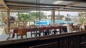 Un espace extérieur aménagé pour les repas, avec des tables et des chaises, une piscine et une vue sur l’ensemble de l’espace piscine.