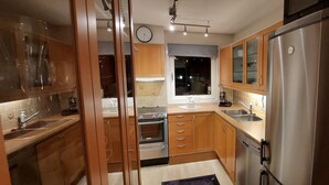 Een moderne keuken met houten kastjes, roestvrijstalen apparatuur en een raam met uitzicht op het binnenland.
