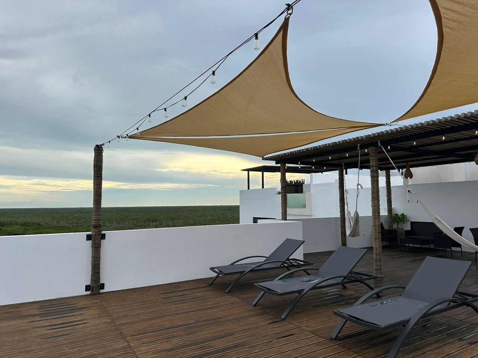 Une terrasse sur le toit, dotée de chaises longues, d’une pergola et offrant une vue sur le paysage.