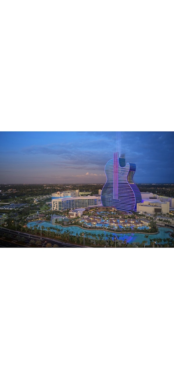 A large building with a guitar-shaped structure, surrounded by a resort area with pools and palm trees. - Stay Near the Action - FIFA Hard Rock Stadium & Beaches (Miami)