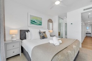 Ein modernes Hotelzimmer mit einem Bett, Nachttischen, einem Deckenventilator und einem großen Fenster.