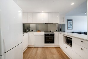Eine moderne Küche mit weißen Schränken, einem Geschirrspüler, einem Backofen und einer Arbeitsplatte mit einem Toaster.