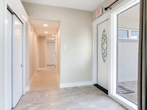 A hallway with a glass door, a door with an 'EXIT' sign, and a tiled floor. - Redington Beach ICW 4BR/2Bath Home 10-min Walk to White Sand Beach (Redington Beach)