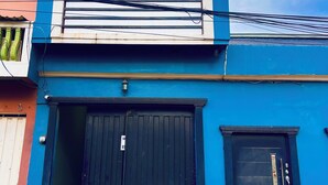A two-story building with a blue facade, a black garage door, and a small window. - House 1 centrally located, 8 (up to 14 people) in san blas neighborhood, Comayagua (Comayagua)