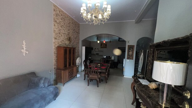 A living room with a sofa, a dining table, and chairs. There is a chandelier, a cabinet, and a television. - House 1 centrally located, 8 (up to 14 people) in san blas neighborhood, Comayagua (Comayagua)
