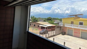 A view from a window overlooking a street with buildings, a car, and a clear sky. - House 1 centrally located, 8 (up to 14 people) in san blas neighborhood, Comayagua (Comayagua)