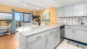 Une cuisine moderne avec des meubles blancs, un grand îlot central et une vue sur l’extérieur.