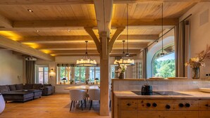 A spacious living area with a wooden ceiling, a dining table, and a kitchen with a large window. - Landhüüs Oeverdiek by Interhome (Niendorf)