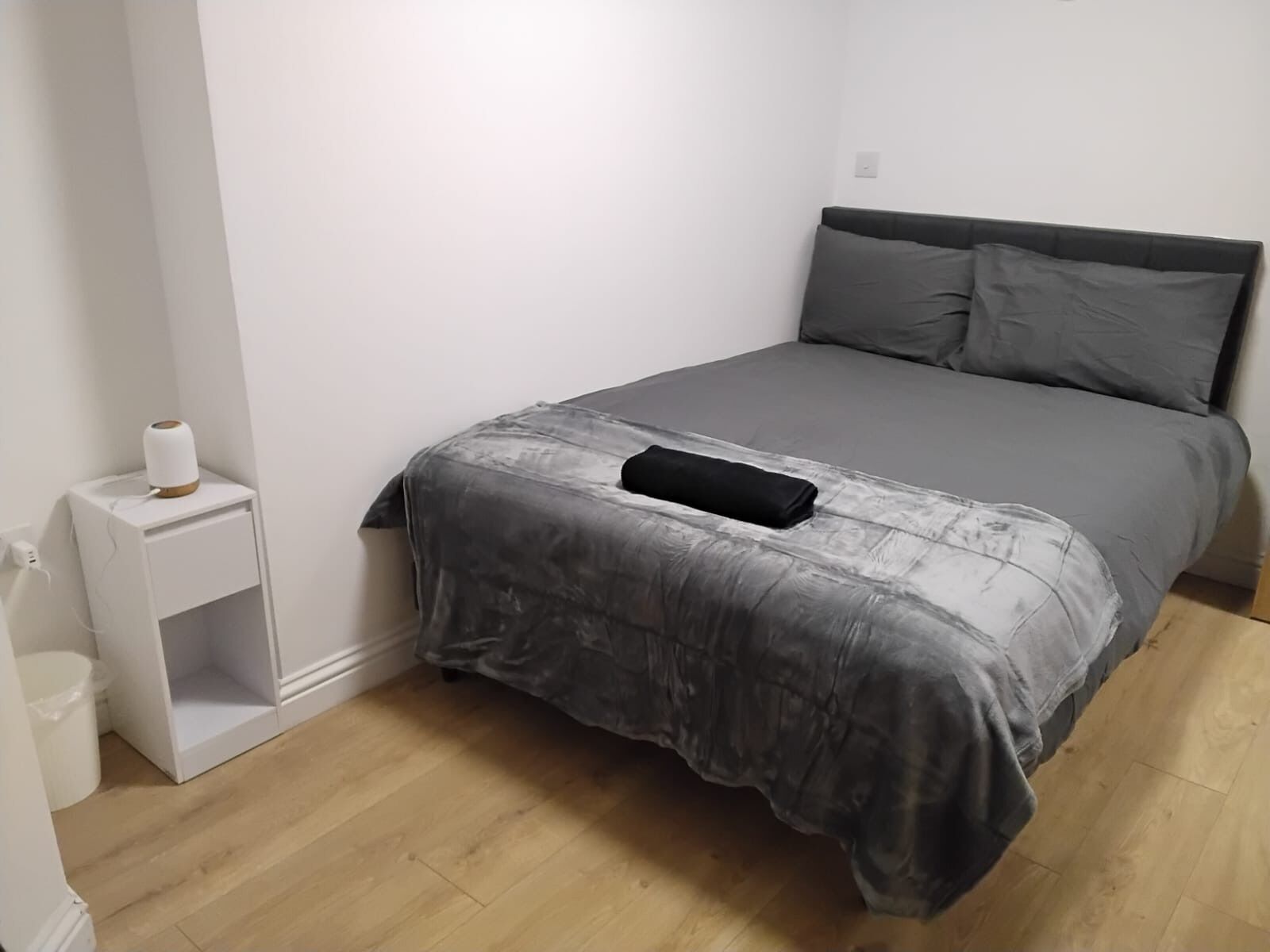 A bedroom with a bed, a bedside table, and a nightstand.