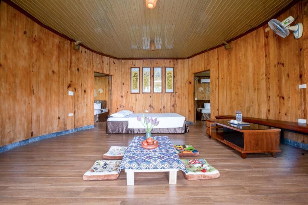 A wooden room with a bed, a table with a vase, and a bench.