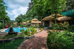 Una piscina al aire libre, sombrillas, sillones reclinables de piscina