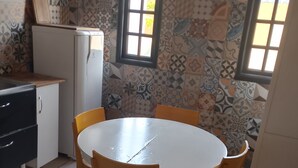 Een keuken met een witte tafel en stoelen, een koelkast en behangen muren.