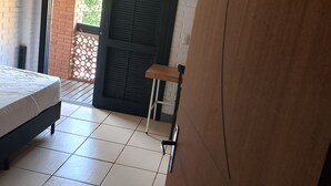 Een slaapkamer met een bed, een tafeltje en een deur naar buiten.