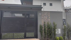 A modern two-story house with a black gate, a brick wall, and a small window. - Refuge 1 Indaiá Beach Bertioga 150 meters from the sea (Bertioga)