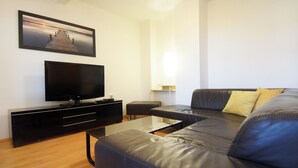 Ein modernes Wohnzimmer mit Flachbildfernseher, einer Couch und einem Couchtisch.