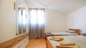 Ein Schlafzimmer mit zwei Betten, Holzboden, einem Kleiderschrank und einem großen Spiegel.