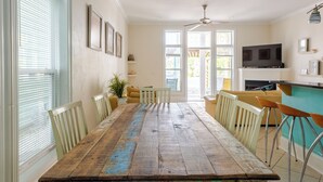 A dining area with a wooden table, chairs, and a television on a stand. - BeachDaze - Crosswalk to Beach Access, Private Pool (Panama City)