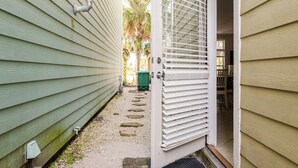 A narrow pathway leading to a house with a white door and a window with blinds. - BeachDaze - Crosswalk to Beach Access, Private Pool (Panama City)