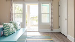 A room with a bench, a striped rug, and a door leading to an outdoor area. - BeachDaze - Crosswalk to Beach Access, Private Pool (Panama City)