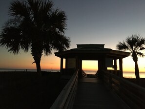 A wooden gazebo with a roof, surrounded by palm trees, overlooking a beach at sunset. - BeachDaze - Crosswalk to Beach Access, Private Pool (Panama City)