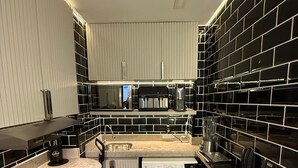 Eine moderne Küche mit integrierter Waschmaschine und Trockner, Edelstahlgeräten und einer schwarz-weißen Küchenrückwand.